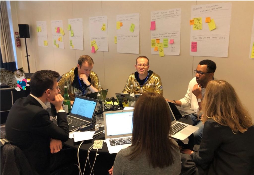 Two holden hoodies and others staring at laptops, surrounded by sticky notes