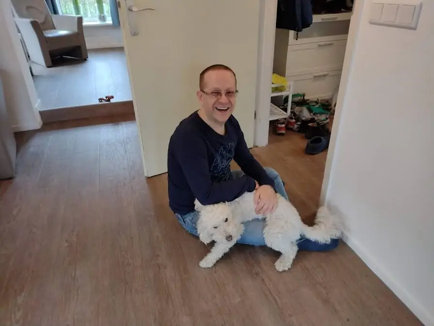 Paul smiling broadly, with his dog Jessy, in his lap. Whether Jessy wants to be on the lap isn't entirely clear.