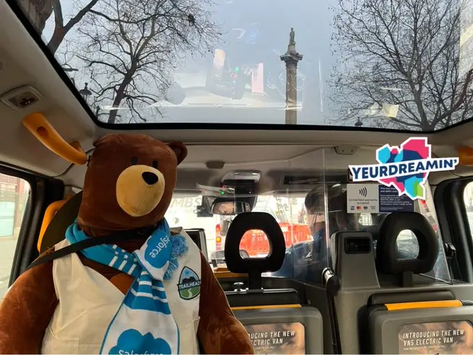 Cody driving past Nelson's Column, in London, in a black cab, with the YeurDreamin' logo plastered over the image