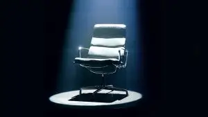 A black office chair with a harsh light beamed in above it.