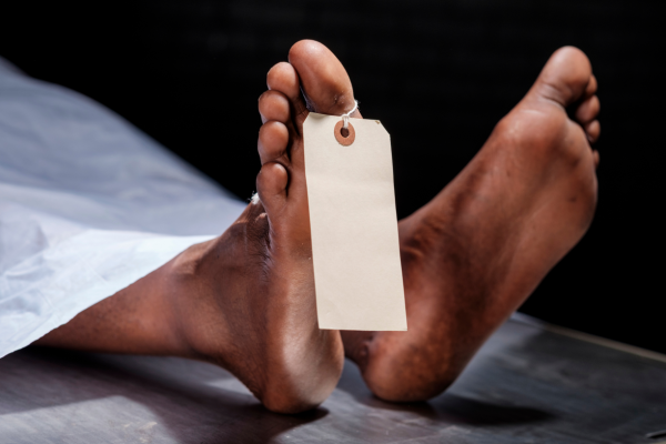 Pictory of a deal body, clearly in a mortuary or hospital setting, as there is a tag on the end of their foot