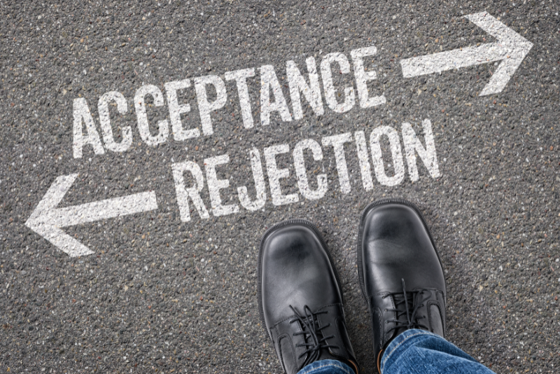 Someone standing at a sign which has acceptance pointing in one direction, and rejection pointing in another